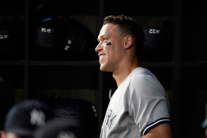 New York Yankees’ Aaron Judge smiles in the dugout after hitting a solo home run, his 62nd of the season, during the first inning in the second baseball game of a doubleheader against the Texas Rangers in Arlington, Texas, Tuesday, Oct. 4, 2022. With the home run, Judge set the AL record for home runs in a season, passing Roger Maris.